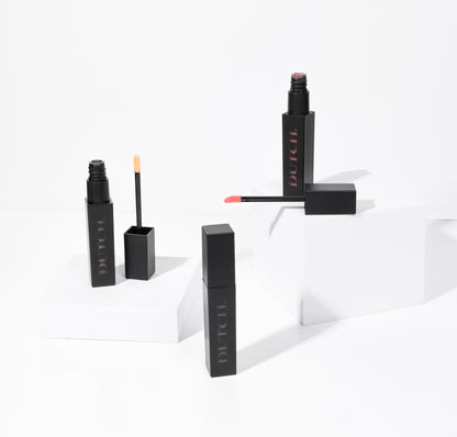 Three tubes of lipgloss in different colors. The tubes are matte black with DUTCH. transparant shown in it. De lipgloss colors are called Hope (transparant), High (bronze) and Hype (coral).
